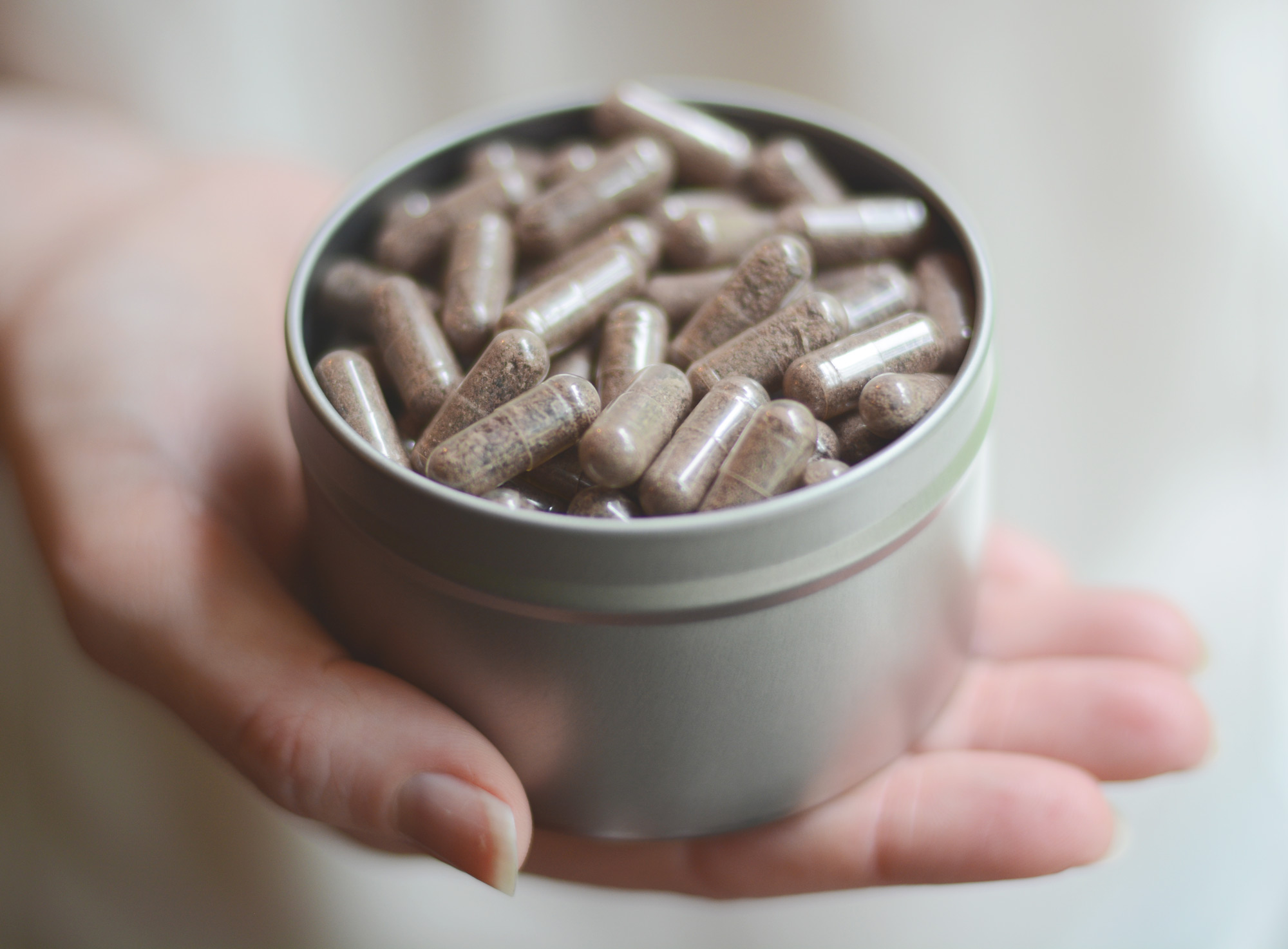 Tin of placenta pills on an open hand shows the benefits of placenta encapsulation