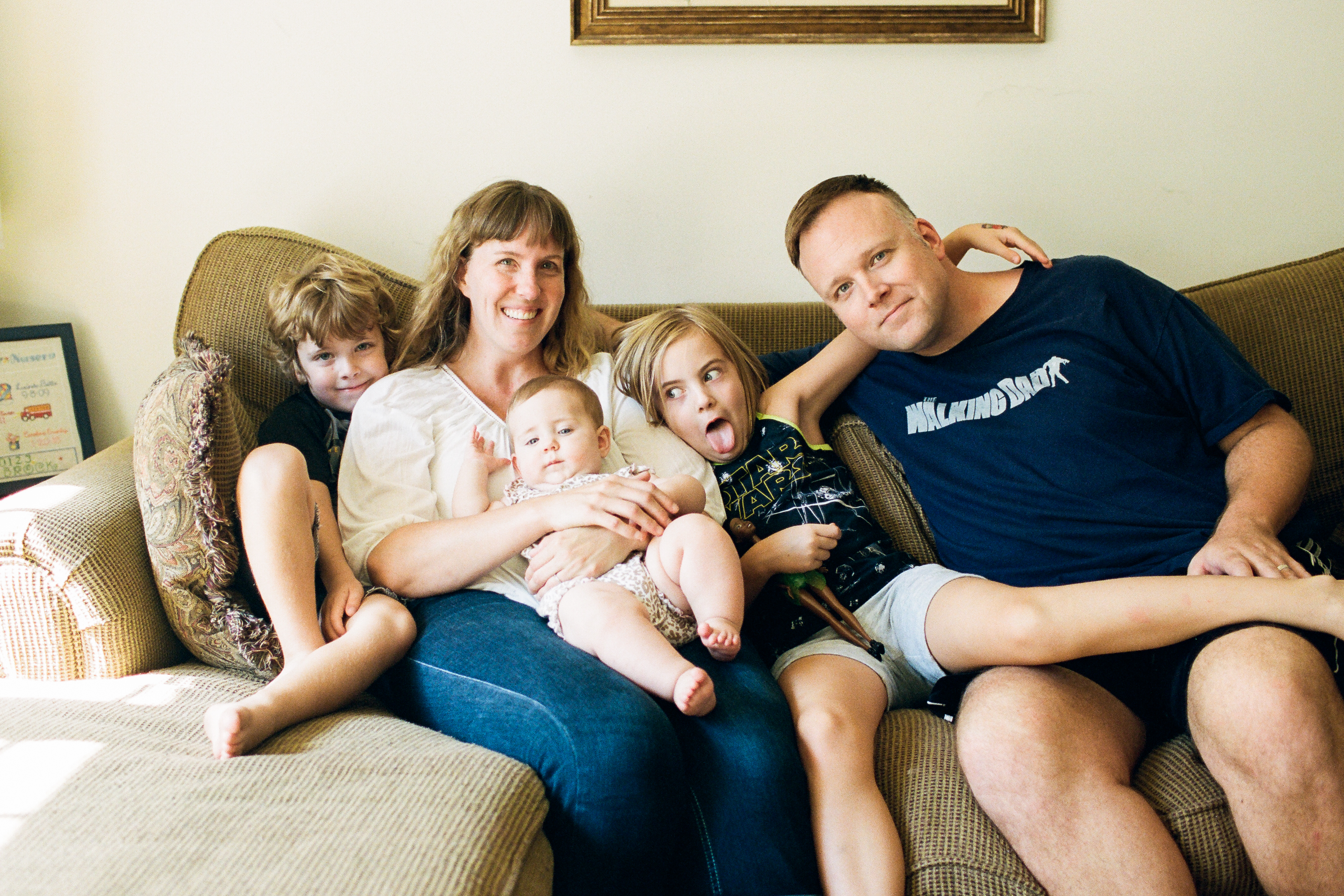 Contact Jenny Corbett! Jenny Corbett is pictured with her family, two young children and her husband on a couch, with her baby on her lap. 